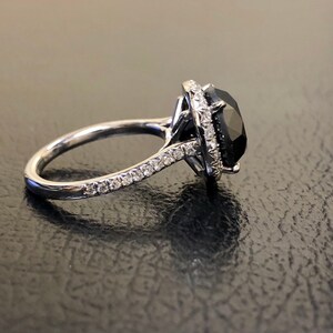 May include: A silver ring with a large black gemstone surrounded by a halo of smaller white gemstones.