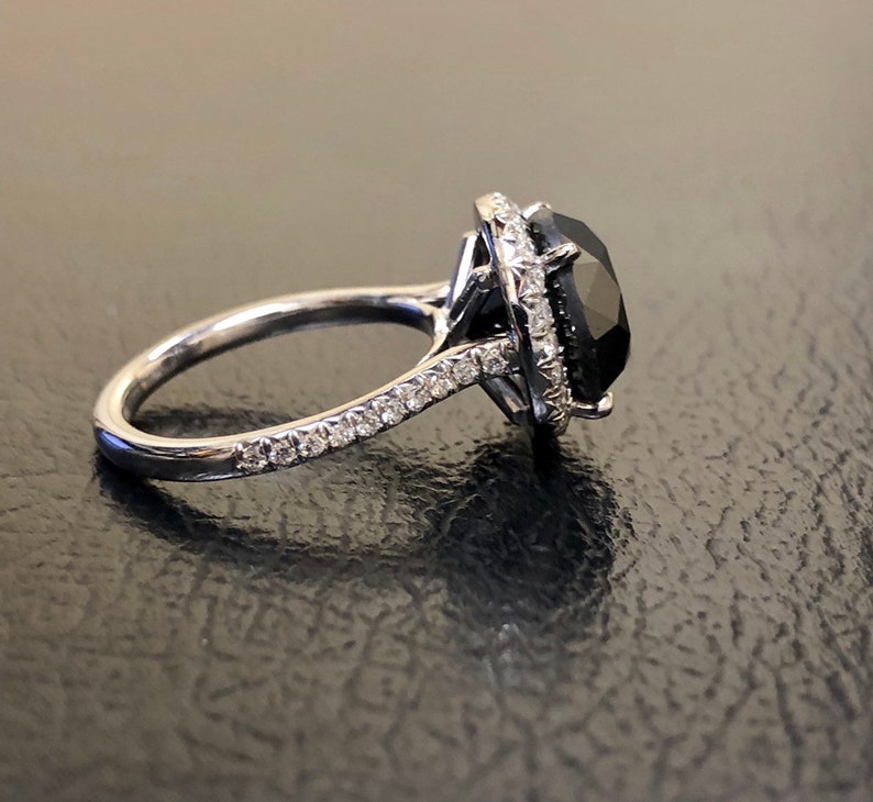 May include: A silver ring with a large black gemstone surrounded by a halo of smaller white gemstones.