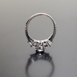 May include: A silver ring with a row of small diamonds around the band and a larger diamond in the centre.