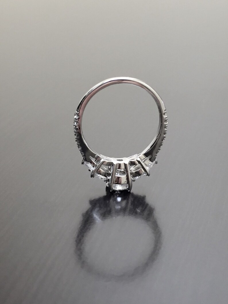 May include: A silver ring with a row of small diamonds around the band and a larger diamond in the centre.