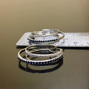 May include: Two pairs of silver hoop earrings with a double row of blue and white gemstones. The earrings are shown on a white ruler with markings in centimetres.