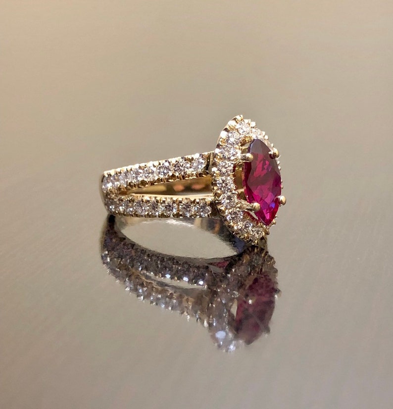 May include: A gold ring with a large, marquise-shaped ruby surrounded by a halo of smaller diamonds. The ring has a double band with diamonds set in the metal.