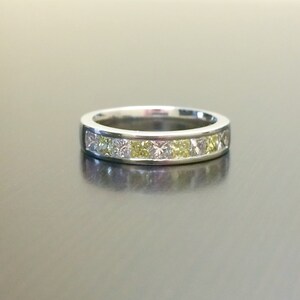 May include: A silver band ring with a row of clear and yellow princess-cut diamonds.