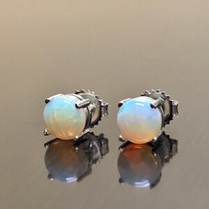 May include: A pair of silver stud earrings with round white opal gemstones.