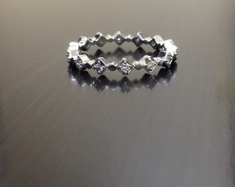 May include: A silver band ring with a row of small, square-shaped diamonds.
