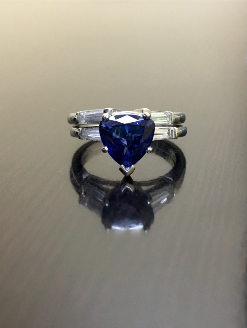 May include: A heart-shaped blue sapphire engagement ring with a white gold band and smaller diamonds on the band.