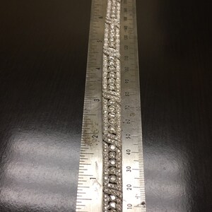 Puede incluir: Un brazalete de plata con una doble fila de diamantes redondos y una fila m&aacute;s peque&ntilde;a de diamantes pav&eacute;. El brazalete se mide con una regla, mostrando que tiene aproximadamente 6 cm de largo.