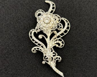 Broche vintage "Avon" con flor de filigrana plateada y diamantes de imitación.