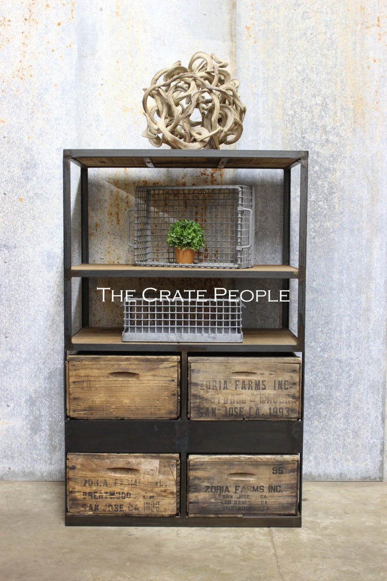 May include: A black metal shelving unit with wooden shelves and drawers. The shelves are decorated with wire baskets and a small potted plant. The drawers are made of wood and have labels that say "Zoria Farms Inc." and "San Jose CA 1993".