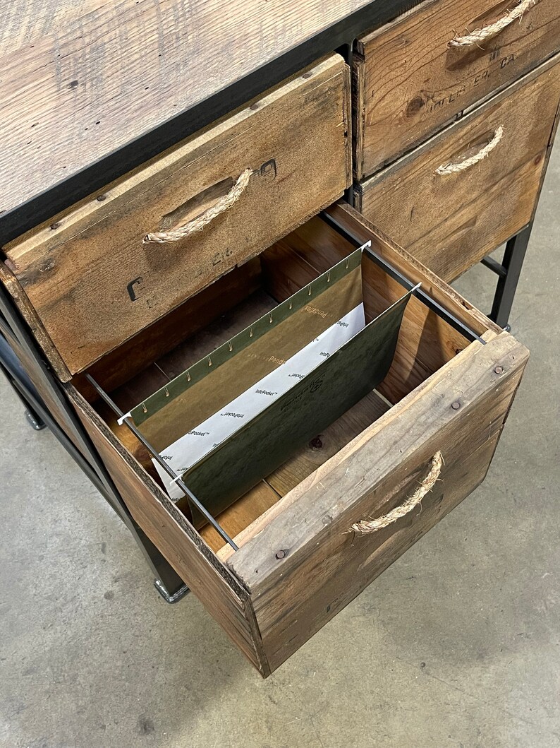 May include: A wooden file cabinet with five drawers. The drawers have rope handles and are made of reclaimed wood. The bottom drawer is open and shows a hanging file folder.