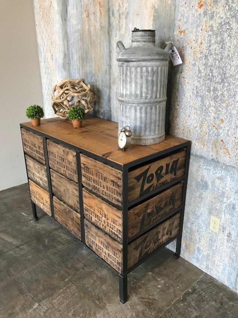 May include: A black metal frame dresser with six drawers made from reclaimed wood crates. The drawers are labeled with the text "Zoria Farms, Inc." and "Brentwood & Madera, San Jose, CA 1993".