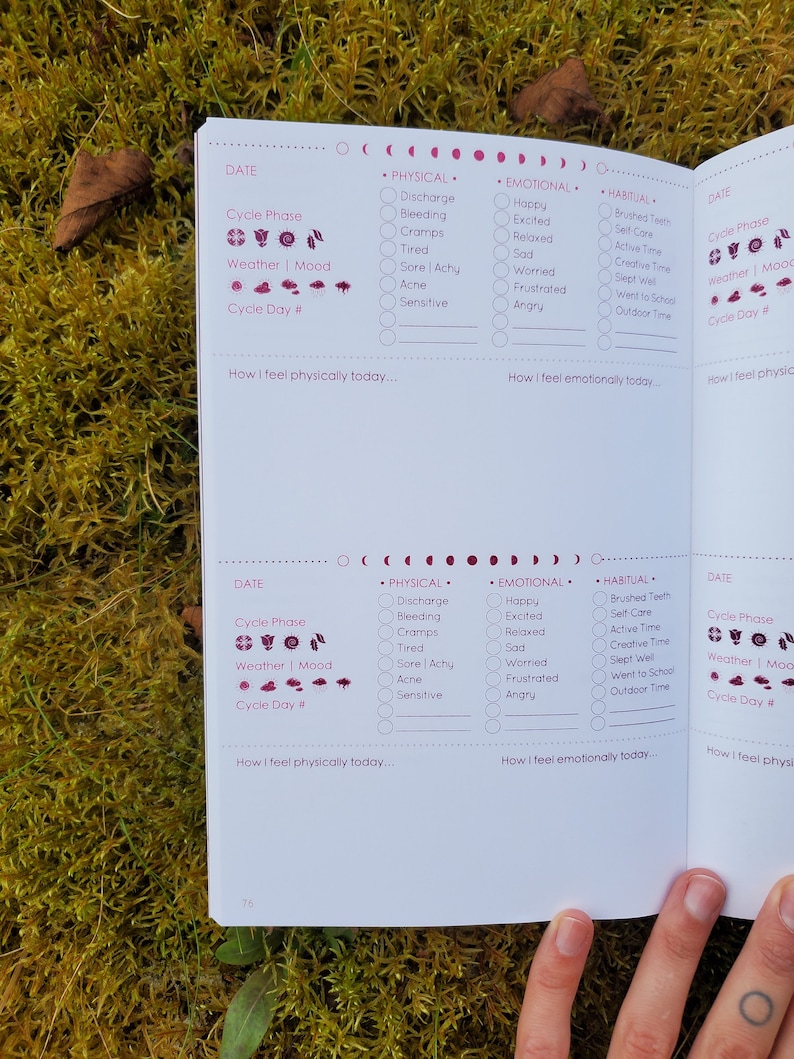 May include: A two-page spread from a pink and white journal with a section for tracking physical, emotional, and habitual activities. The journal includes sections for tracking cycle phase, weather, and mood. The journal has a pink and white color scheme with a pink moon and sun graphic.