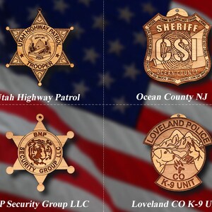 May include: Four wooden ornaments shaped like stars and shields with law enforcement logos. The ornaments feature the logos for the Utah Highway Patrol, Ocean County NJ Sheriff's Department, BNP Security Group LLC, and Loveland CO K-9 Unit.