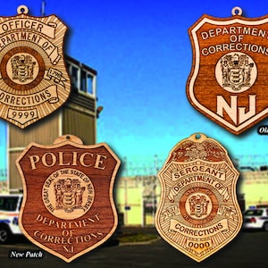 May include: Three wooden badges with the text "Department of Corrections" and the state seal of New Jersey. The badges are in the shape of a shield and have a brown wood grain finish. The text "Old Patch" and "New Patch" are written below the badges.