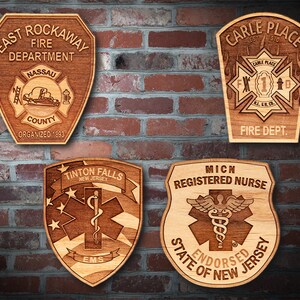 May include: Four wooden plaques with engraved designs. The top left plaque is for the East Rockaway Fire Department, Nassau County, organized in 1893. The top right plaque is for the Carle Place Fire Department, established in 1910. The bottom left plaque is for Tinton Falls, New Jersey, EMS. The bottom right plaque is for a Michigan Registered Nurse, endorsed by the State of New Jersey.