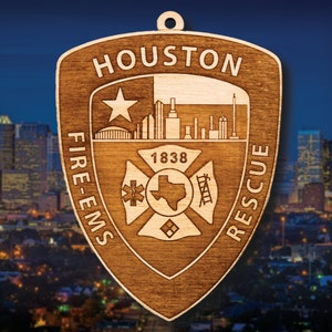 May include: Wooden ornament shaped like a shield with the words "Houston Fire-EMS Rescue" and the city skyline. The ornament also features a star, the year 1838, and a fire department logo.