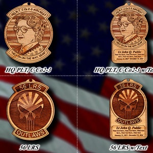 Könnte beinhalten: Vier Holzornamente mit Holzmaserung. Zwei Ornamente zeigen ein Cartoon-Bild einer Frau mit dem Text "HQ PLT, C Co2-3 AVN REGT" und "HELP IN ON THE WAY, DEAR". Die beiden anderen Ornamente zeigen einen Schädel mit dem Text "56 LRS OUTLAWS". Eines der Schädelornamente trägt den Text "Lt John Q. Public" und Daten.