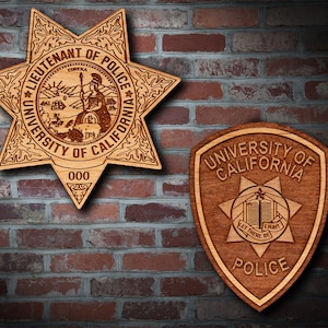 May include: Two wooden police badges, one a traditional star shape with the text "Lieutenant of Police University of California 000" and the other a shield shape with the text "University of California Let There Be Light Police".