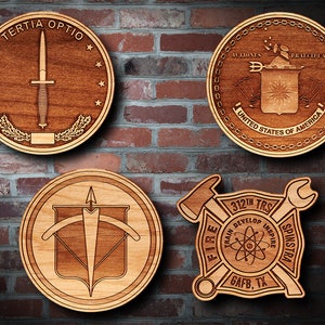May include: Four wooden plaques with different designs. The top left plaque has a dagger with the text "TERTIA OPTIO" around it. The top right plaque has a shield with a star and the text "ACTIONES PRALCIPEAL UNITED STATES OF AMERICA". The bottom left plaque has a bow and arrow. The bottom right plaque has a wrench, a hammer, and the text "FIRE 312TH TRS TRAIN DEVELOP INSPIRE GAFB, TX".
