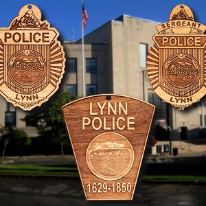 May include: Three wooden ornaments featuring the Lynn Police Department logo. The first ornament is a traditional police badge with the words "Police" and "Lynn" inscribed. The second ornament is a similar badge with the word "Sergeant" above "Police". The third ornament is a shield-shaped plaque with the words "Lynn Police" and "1629-1850" inscribed.