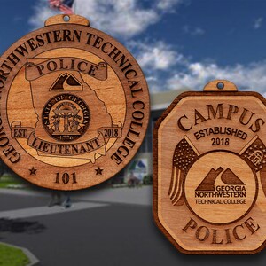 May include: Two wooden ornaments with the text "Georgia Northwestern Technical College Police" and "Campus Established 2018". The first ornament is round and features a state of Georgia outline with the words "Police", "Lieutenant", and "101". The second ornament is a hexagon shape with a mountain range and two flags.