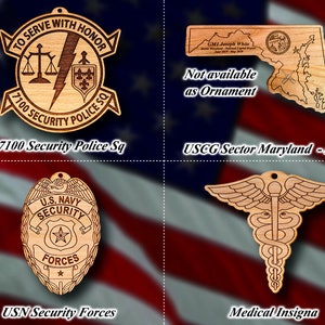 May include: Four wooden ornaments with different designs. The top left ornament is a brown shield with the text "TO SERVE WITH HONOR" and "7100 SECURITY POLICE SQ". The top right ornament is a brown outline of the state of Maryland with the text "USCG Sector Maryland - NCR". The bottom left ornament is a brown shield with the text "U.S. NAVY SECURITY FORCES". The bottom right ornament is a brown medical insignia with a snake and wings.