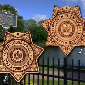 Könnte beinhalten: Zwei sternförmige Abzeichen aus Holz mit dem Text "Office of the Sheriff County of Suffolk" und "Corrections Officer Suffolk County Sheriff" mit dem Staatssiegel von New York in der Mitte.