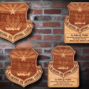 May include: Wooden plaques with the HQ Arizona Air National Guard emblem, featuring an eagle, star, and sunburst design. Some plaques include personalized text and dates. The plaques are displayed against a brick wall.
