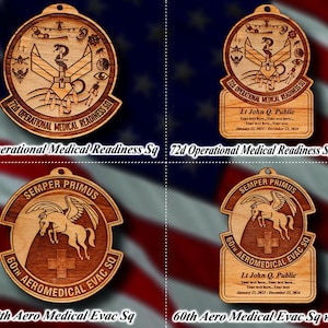 May include: Wooden military-themed ornaments with intricate laser-cut designs. The ornaments feature emblems, text, and a pegasus. Some include personalized text. The text includes "72d Operational Medical Readiness Sq" and "60th Aero Medical Evac Sq".
