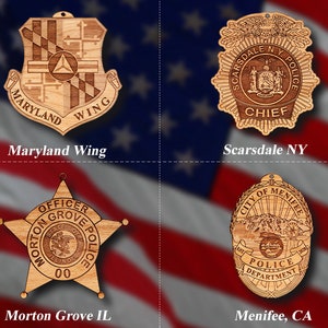 May include: Four wooden ornaments featuring police department badges. The top left ornament is a Maryland Wing badge. The top right ornament is a Scarsdale NY Police badge. The bottom left ornament is a Morton Grove IL Police badge. The bottom right ornament is a Menifee CA Police badge.