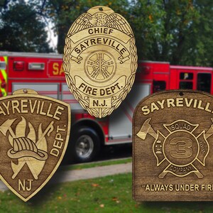 May include: Three wooden firefighter badges with the text "Sayreville Fire Dept. NJ" and "Always Under Fire". The badges feature a firefighter helmet, crossed axes, and a fire hose.