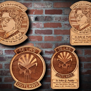 Könnte beinhalten: Vier Holzplaketten mit lasergravierten Designs. Zwei Plaketten zeigen einen Totenkopf mit Knochen und den Text "56 LRS OUTLAWS". Die anderen beiden Plaketten zeigen ein Frauenporträt mit dem Text "HQ PLT, C Co 2-3 AVN REGT" und "HELP I ON THE WAY, DEAR".
