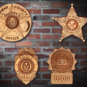 May include: Four wooden plaques with engraved designs of law enforcement badges. The top left plaque is round and features a star with the text "Lamar County Sheriff's Office". The top right plaque is a star shape with the text "Deputy Sheriff Sherburne County". The bottom left plaque is a shield shape with the text "Adult Probation State of Connecticut". The bottom right plaque is a round shape with the text "Port Chester Police Detective".