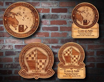 May include: Wooden plaques with engraved designs and text. Two circular plaques feature a map and text, including "EQUATEUR CROIX DU SUD." Two rectangular plaques include text: "Lt John Q. Public." The other two plaques have a shield design and text: "U.S. MILITARY ENTRANCE PROCESSING COMMAND."