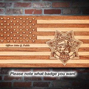 May include: A wooden American flag with a California Highway Patrol badge. The badge is a gold star with the words "California Highway Patrol" around the edge. The badge also has the words "Eureka" and "Officer" on it. The text "Officer John Q. Public" is below the flag.
