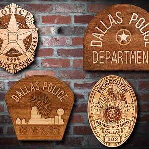 May include: Four wooden plaques with different Dallas Police Department designs. The top left plaque features a star with the letters "D" and "P" inside, surrounded by a rope design. The top right plaque reads "Dallas Police Department". The bottom left plaque reads "Dallas Police Crime Scene" and features a skyline with a fingerprint. The bottom right plaque features a badge with a woman holding scales and a sword, and the text "Prosecutor District Attorney Dallas 302".