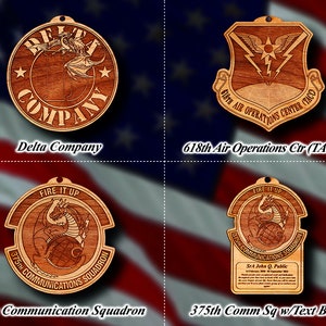 May include: Four wooden ornaments featuring a dragon design. The top left ornament is round and reads "Delta Company". The top right ornament is shield-shaped and reads "618th Air Operations Center (TACC)". The bottom left ornament is round and reads "375th Communications Squadron". The bottom right ornament is rectangular and reads "375th Communications Squadron" with a text box below that reads "SrA John Q. Public".