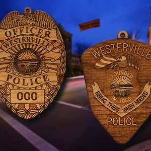 May include: Two wooden police badges, one with the text "OFFICER WESTERVILLE POLICE 000" and the other with the text "WESTERVILLE FOUNDED IN 1858 BEING THERE WHEN NEEDED POLICE".