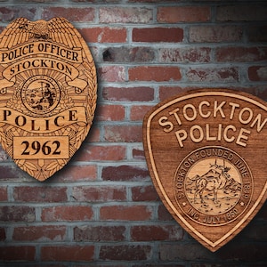 May include: Two wooden plaques with the Stockton Police Department logo. The first plaque is a traditional police badge with the words "Police Officer Stockton" and "Police" and the badge number "2962". The second plaque is a shield shape with the words "Stockton Police" and "Founded June 1849 Inc. July 1850".