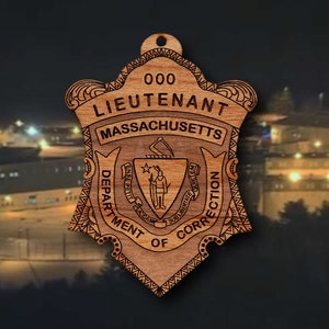 May include: A wooden ornament shaped like a shield with the text "000 Lieutenant Massachusetts Department of Correction" and a crest with a star and a figure holding a sword.