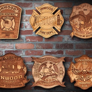 Könnte beinhalten: Sechs Holzplaketten mit verschiedenen Feuerwehrlogos. Die Plaketten sind alle in einem ähnlichen Stil gehalten, mit einem braunen Holzgrund und weißen Schriftzügen. Die Logos zeigen verschiedene Feuerwehrsymbole, darunter einen Hydranten, eine Leiter und einen Adler. Der Text auf den Plaketten enthält die Wörter "Inwood", "Fire Department", "Engine Company", "Tower Ladder", "Squad" und "Excuse Me Brothers".