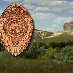 May include: A wooden ornament shaped like a police badge with the text "TROOPER NEBRASKA STATE PATROL" and the number "000".