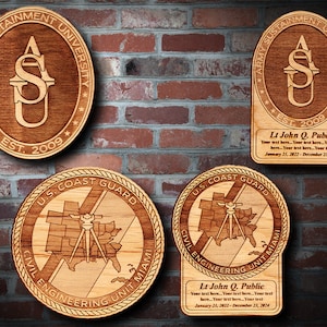 May include: Wooden plaques with engraved designs. Two circular plaques feature the "Army Sustainment University" logo and "U.S. Coast Guard" emblem. Two rectangular plaques include the same logos and text: "Lt John Q. Public" and dates.