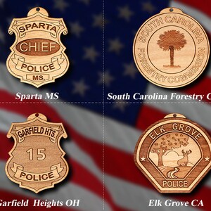 May include: Four wooden ornaments with different designs. The top left ornament is a police badge with the text "SPARTA CHIEF POLICE MS.". The top right ornament is a round disc with the text "SOUTH CAROLINA FORESTRY COMMISSION". The bottom left ornament is a police badge with the text "GARFIELD HTS. 15 POLICE". The bottom right ornament is a hexagonal ornament with the text "ELK GROVE POLICE".