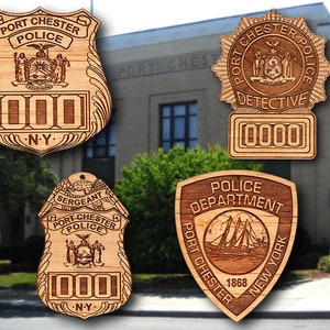 May include: Four wooden police badges with different designs. The badges are engraved with the words "Port Chester Police", "Detective", "Sergeant", and "Police Department". The badges also feature the New York State seal and the year 1868.