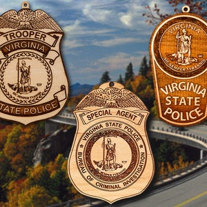 May include: Three wooden ornaments shaped like police badges. The top ornament says "Trooper Virginia State Police" with the Virginia state seal in the center. The middle ornament says "Special Agent Virginia State Police Bureau of Criminal Investigation" with the Virginia state seal in the center. The bottom ornament says "Virginia State Police" with the Virginia state seal in the center.