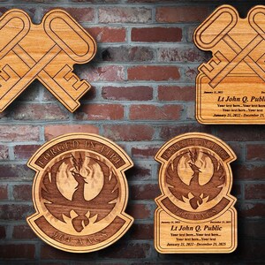 May include: Wooden plaques with laser-cut designs. Two plaques feature crossed keys, while the others display a phoenix emblem with the text "FORGED IN FIRE" and "964 AACS". Some plaques include personalized text.
