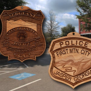 May include: Two wooden police badges with the text "SERGEANT CITY OF JASPER POLICE FIRST MOUNTAIN CITY GA 1857" and "POLICE FIRST MTN. CITY JASPER GEORGIA" engraved on them.