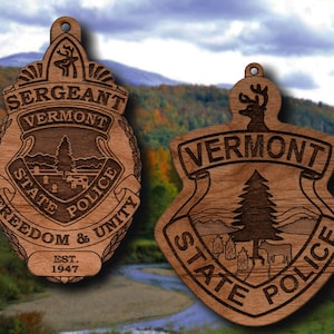 May include: Two wooden ornaments shaped like police badges, one with the text "Sergeant Vermont State Police Freedom & Unity Est. 1947" and the other with the text "Vermont State Police".