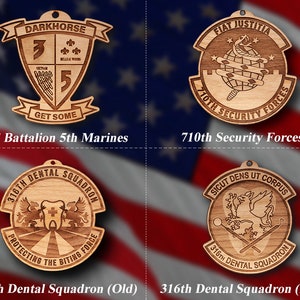 May include: Four wooden ornaments with different military unit insignia. The top left ornament features a shield with the text "DARKHORSE" and "GET SOME". The top right ornament features a circle with the text "FIAT JUSTITIA" and "710TH SECURITY FORCES". The bottom left ornament features a circle with the text "316TH DENTAL SQUADRON" and "PROTECTING THE BITING FORCE". The bottom right ornament features a circle with the text "SICUT DENS UT CORPUS" and "316TH DENTAL SQUADRON".